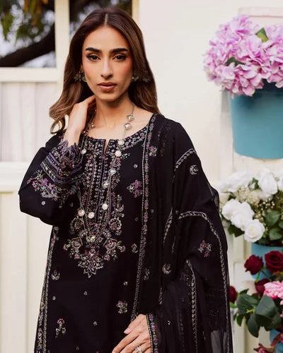 Woman wearing a black embroidered dress with flowers and a building in the background