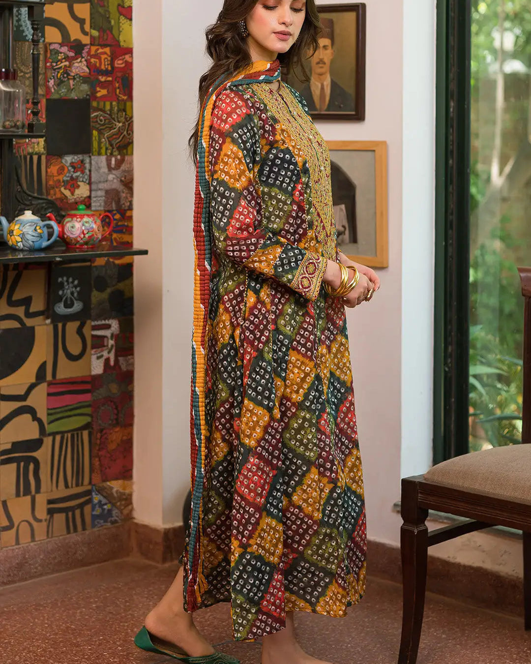 Woman in a colorful patterned outfit standing in a room with decorative elements.
